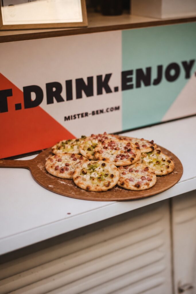 Mini-Pizzen auf Holzbrett vor Café-Schild